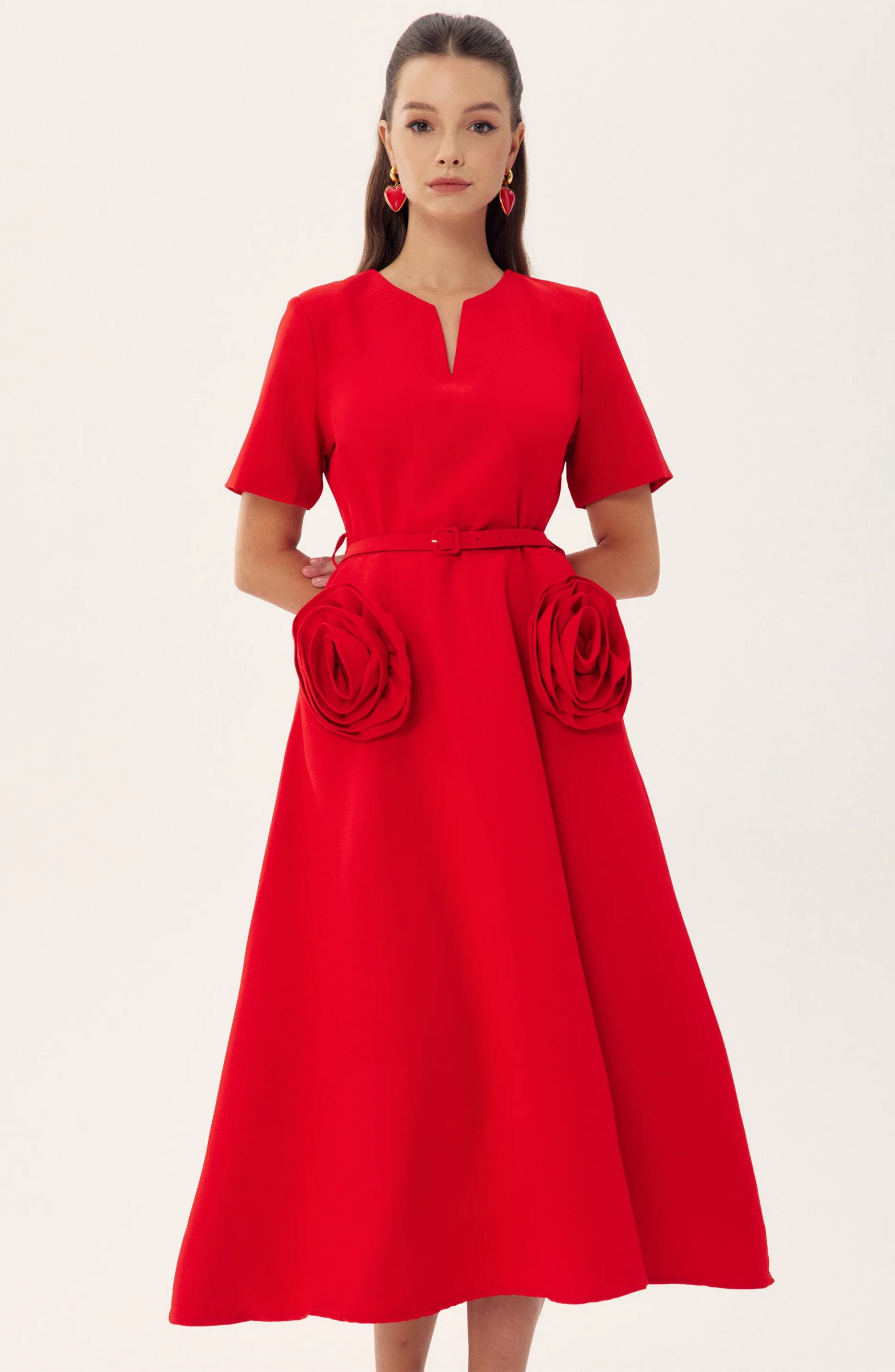 Red - A woman wearing a bright red, short-sleeved midi dress featuring a notched V-neckline, a thin waist belt, and two large 3D rosette embellishments on the A-line skirt.