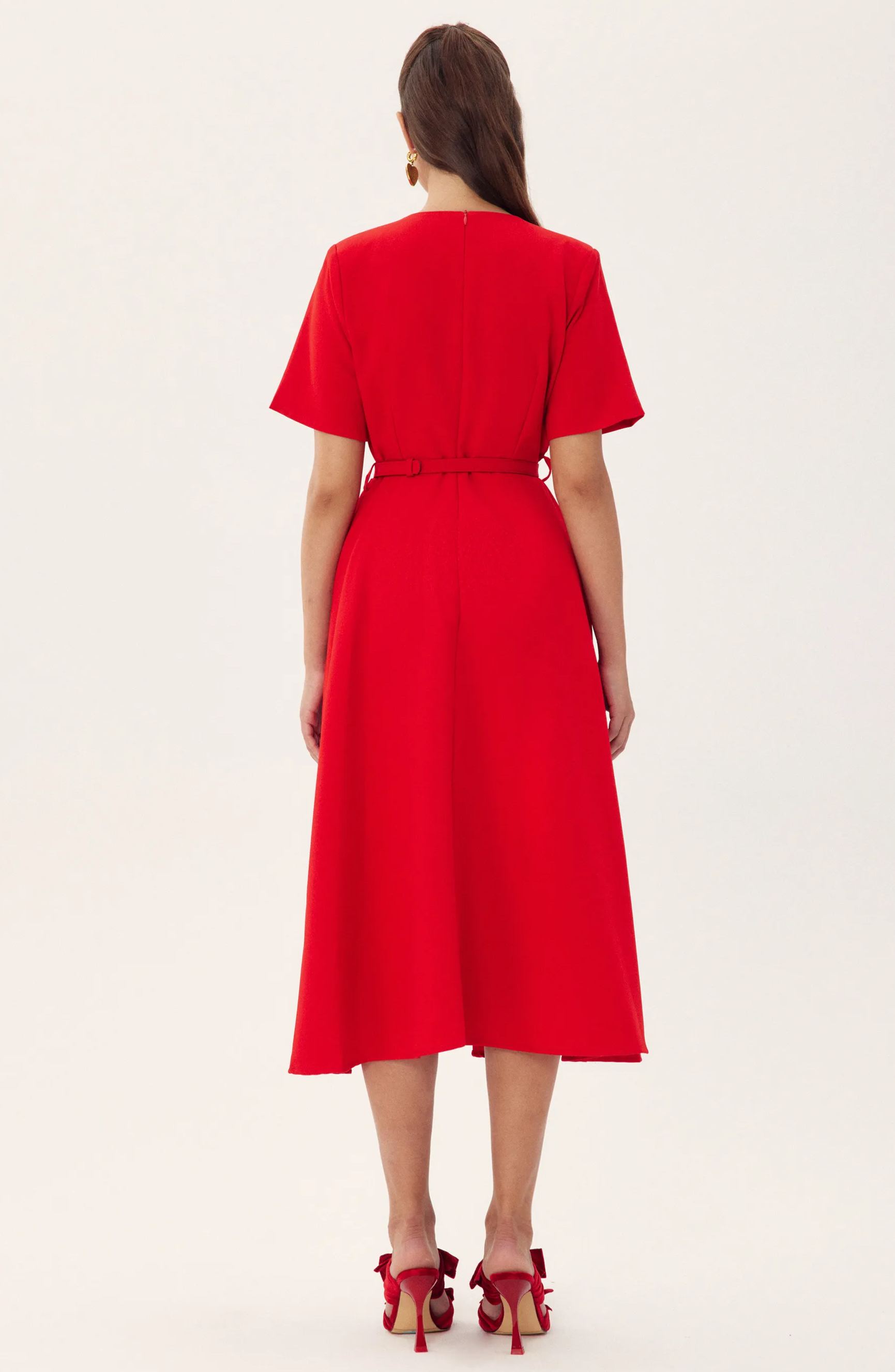 Red - A woman wearing a bright red, short-sleeved midi dress featuring a notched V-neckline, a thin waist belt, and two large 3D rosette embellishments on the A-line skirt.