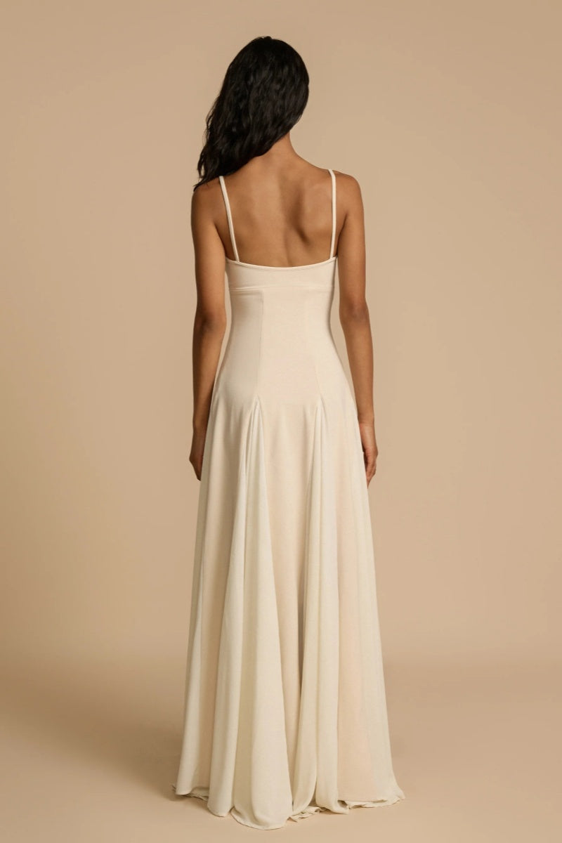 Ivory - A woman wearing a long, cream-coloured maxi dress with a sweetheart neckline, slim straps, and a voluminous skirt with godet pleats.