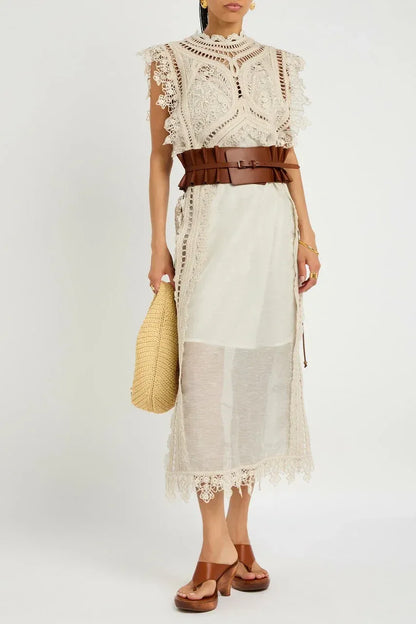 Apricot - A woman wearing a cream-coloured midi dress featuring an intricate crochet overlay with scalloped edges over a semi-sheer slip.