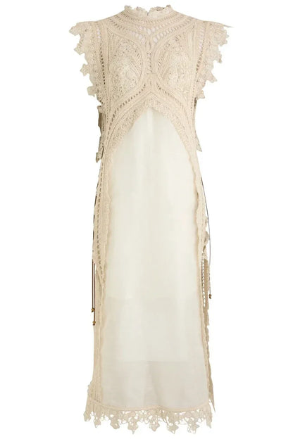 Apricot - A woman wearing a cream-coloured midi dress featuring an intricate crochet overlay with scalloped edges over a semi-sheer slip.