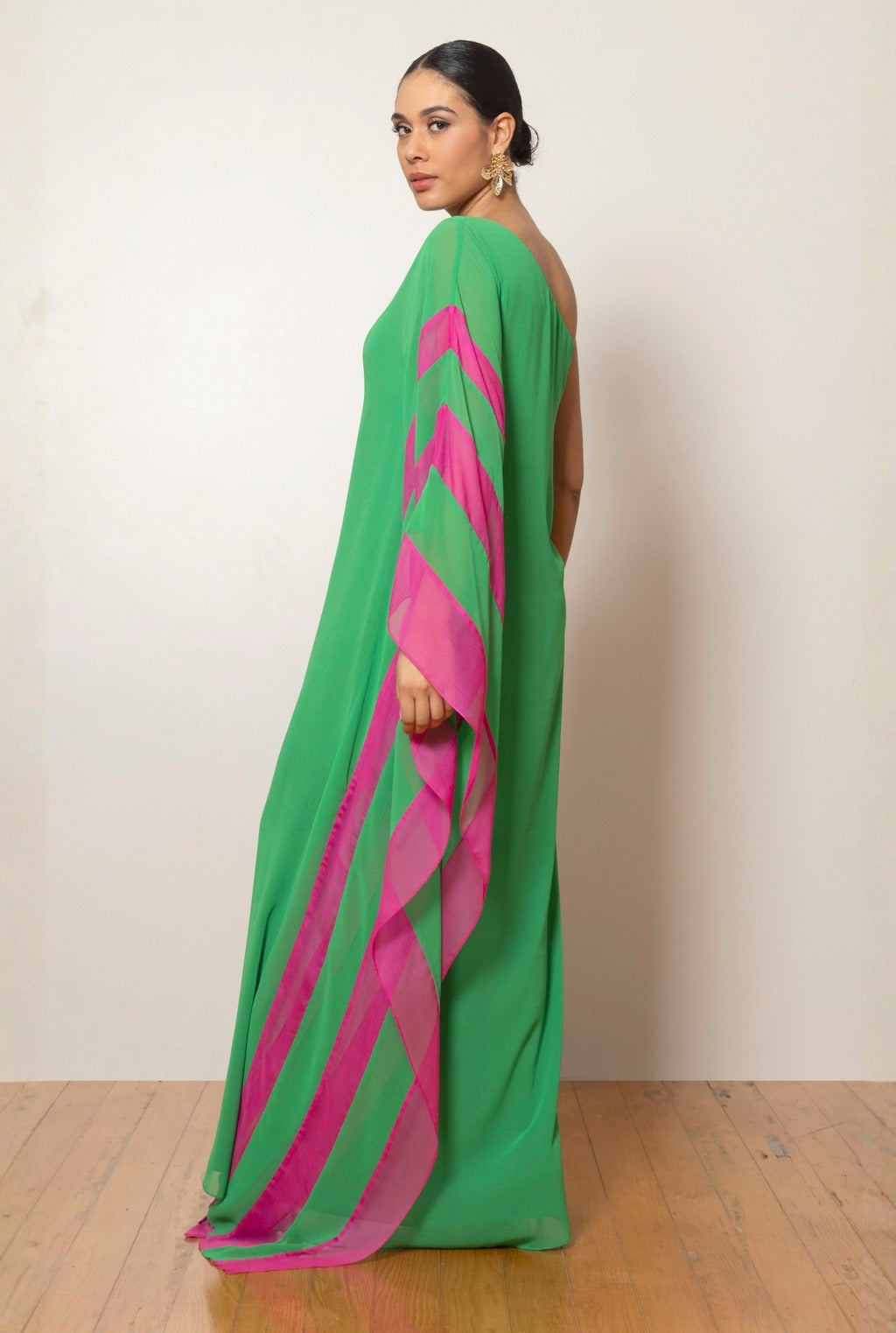 Green - Women's bright green one-shoulder maxi dress featuring a dramatic asymmetrical draped cape sleeve with a vibrant pink contrast trim.