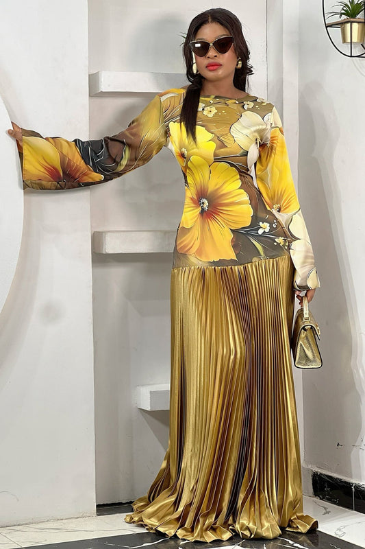 Women's formal maxi dress featuring a high-neck bodice with a large yellow floral print, long flared sleeves, and a contrasting metallic gold pleated drop-waist skirt.