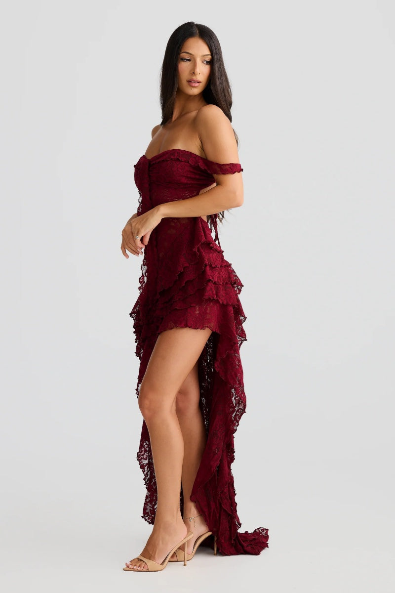 Red - A woman wearing a dark red, off-the-shoulder maxi dress made of floral lace, featuring a ruched bodice, a high front slit with cascading ruffles, and a dramatic back train.