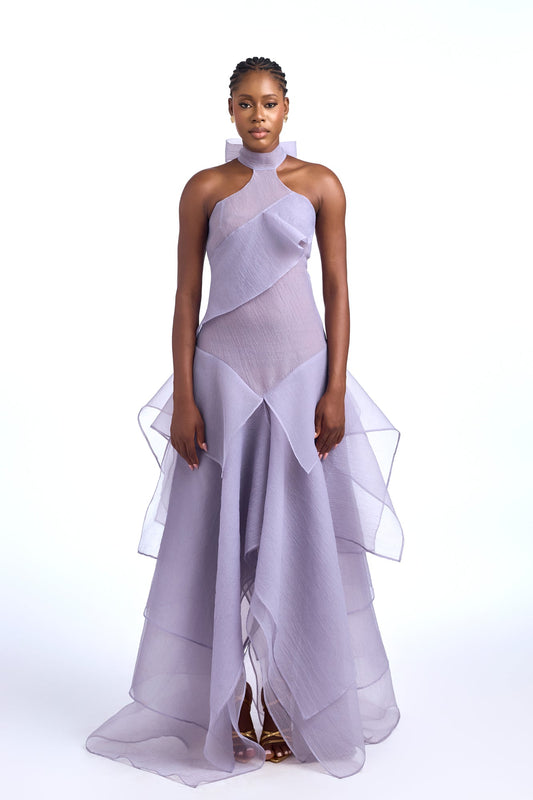 Purple - A model wearing a light purple, sheer maxi dress with a high halter neckline, asymmetrical folded bodice details, and a voluminous, heavily tiered skirt.