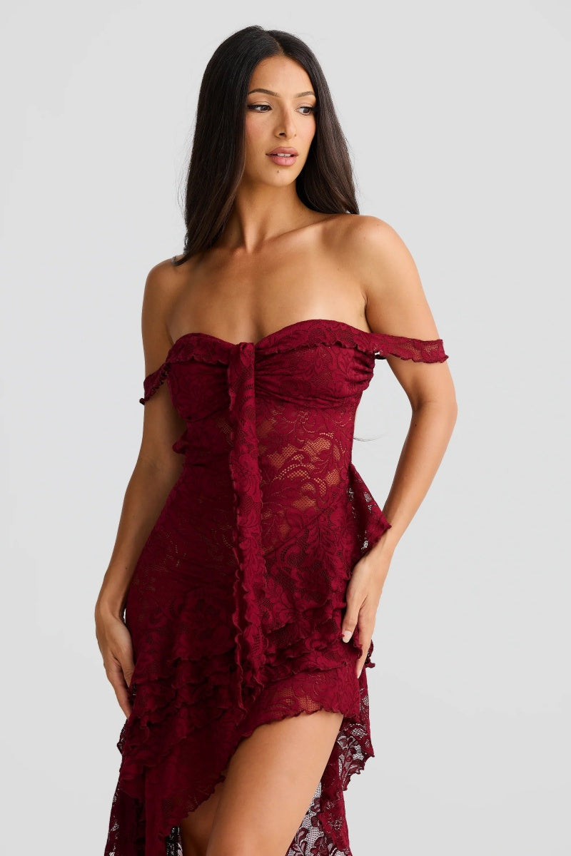 Red - A woman wearing a dark red, off-the-shoulder maxi dress made of floral lace, featuring a ruched bodice, a high front slit with cascading ruffles, and a dramatic back train.