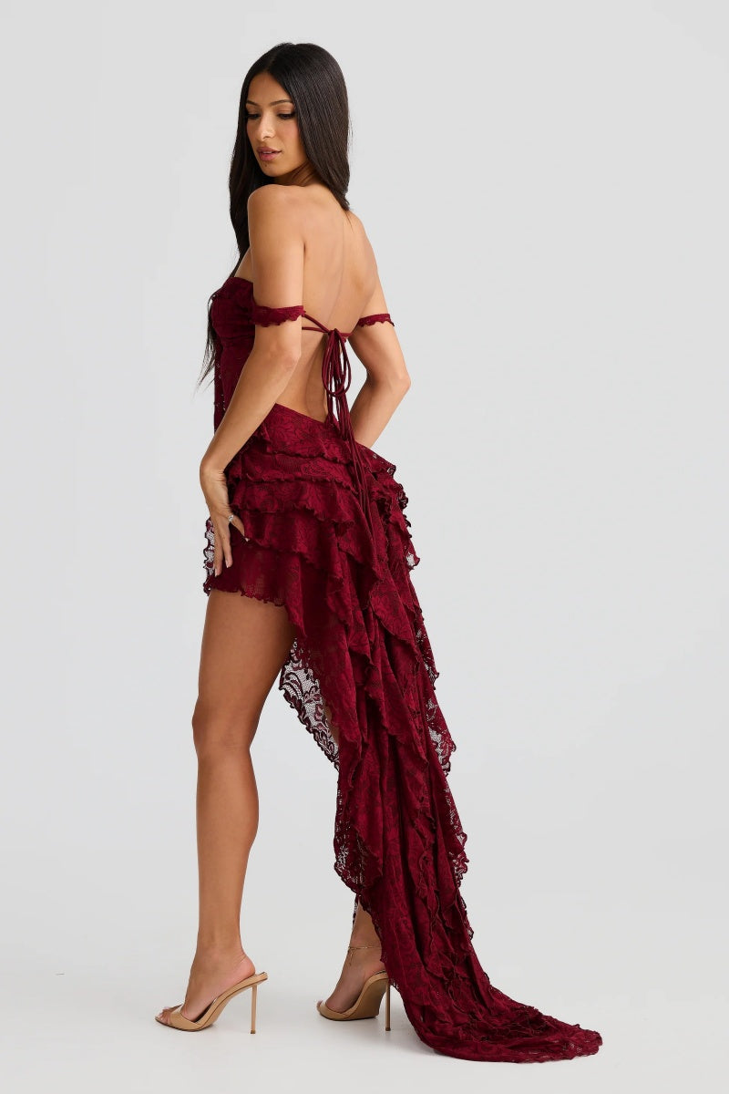 Red - A woman wearing a dark red, off-the-shoulder maxi dress made of floral lace, featuring a ruched bodice, a high front slit with cascading ruffles, and a dramatic back train.