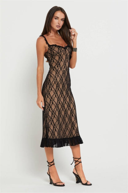 Black - A woman modelling a fitted midi dress featuring a black floral lace overlay over a nude lining, complete with ruffled straps, a corset-style bodice, and a frilled hem.