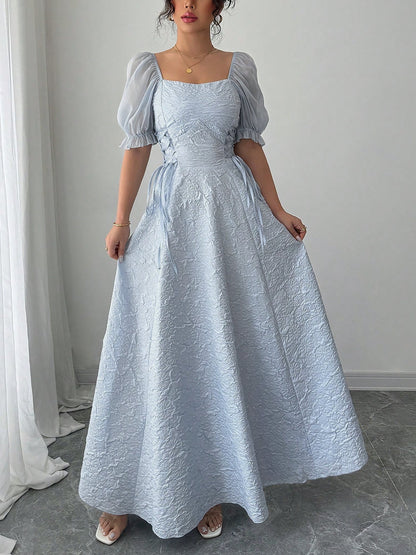 Grey Blue - Model wearing a textured jacquard A-line maxi dress with sheer puff sleeves and side lace-up bodice detailing.