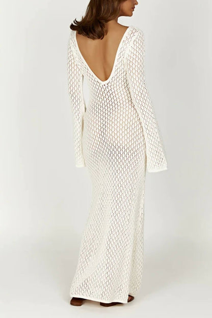 White - A woman wearing a white, semi-sheer crochet maxi dress with long flared sleeves and a deep V-neckline with keyhole detailing, standing outdoors.