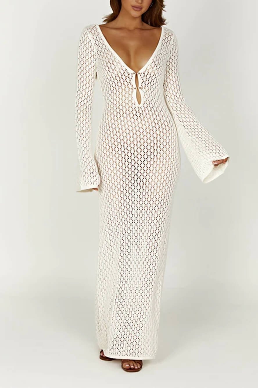 White - A woman wearing a white, semi-sheer crochet maxi dress with long flared sleeves and a deep V-neckline with keyhole detailing, standing outdoors.