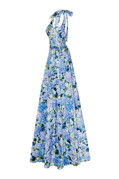 Blue - A woman models an elegant floor-length maxi dress featuring a structured corset bodice, tie-shoulder straps, and a vibrant blue and green floral print on a crisp, voluminous fabric.