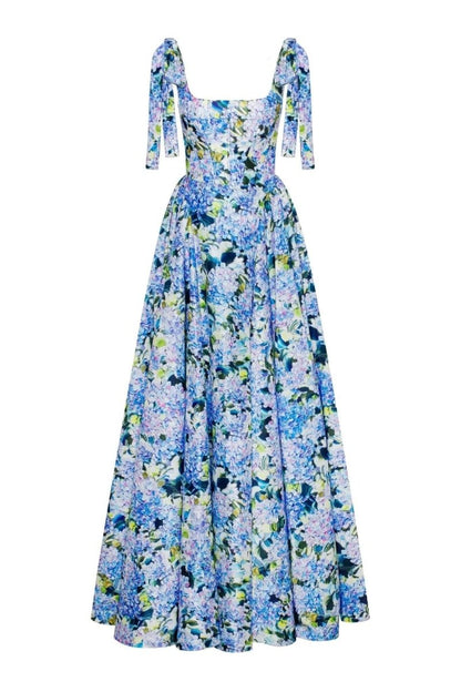 Blue - A woman models an elegant floor-length maxi dress featuring a structured corset bodice, tie-shoulder straps, and a vibrant blue and green floral print on a crisp, voluminous fabric.