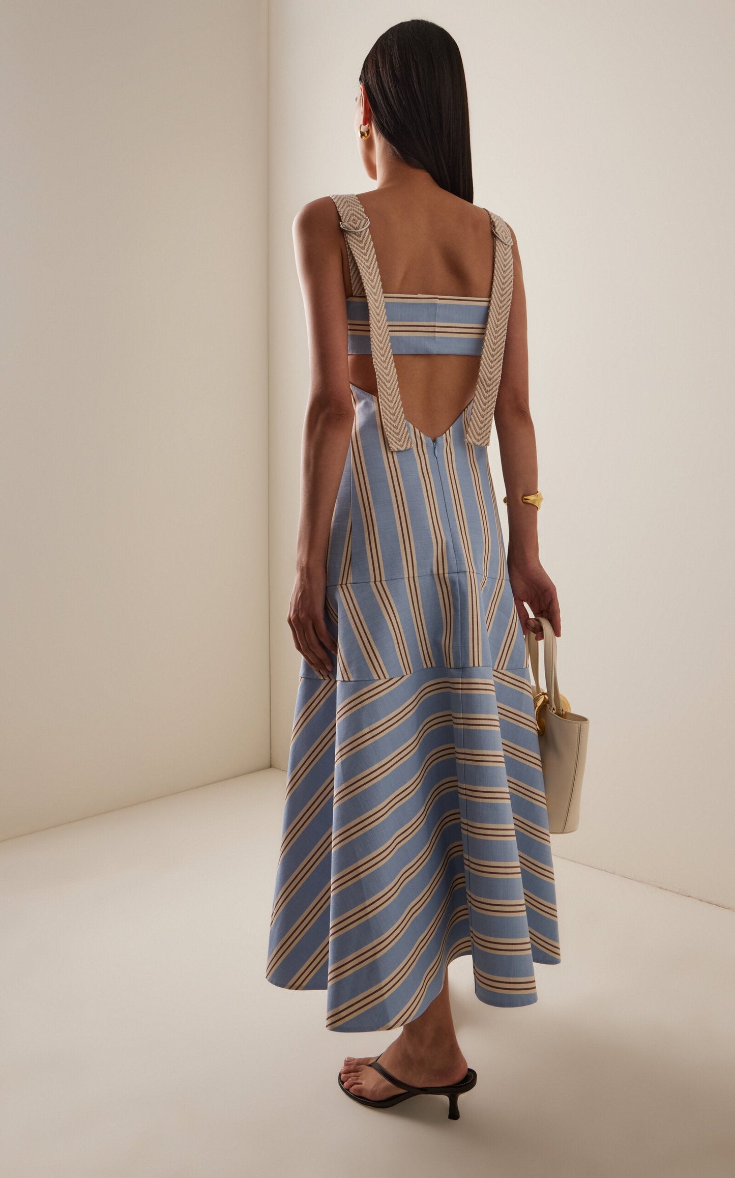 Women's light blue, beige, and brown striped midi dress featuring wide textured straps, side waist cutouts, and a panelled A-line skirt creating a chevron stripe effect.