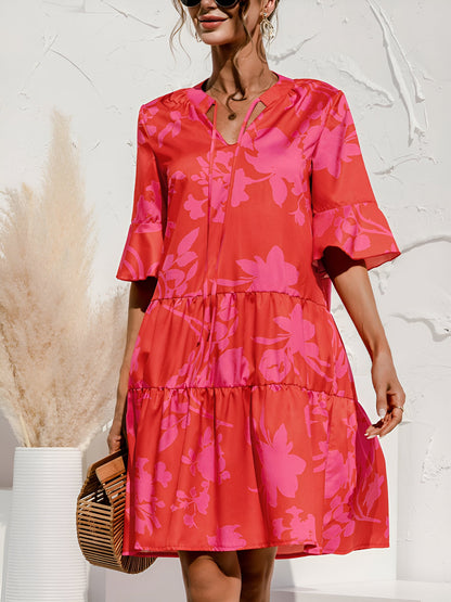 Rose Red - Model wearing a woven leopard print v-neck tiered mini dress with flutter sleeves and neckline tie details, holding a structured bamboo handbag.