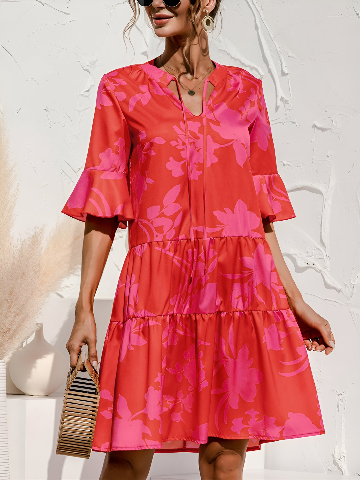 Rose Red - Model wearing a woven leopard print v-neck tiered mini dress with flutter sleeves and neckline tie details, holding a structured bamboo handbag.