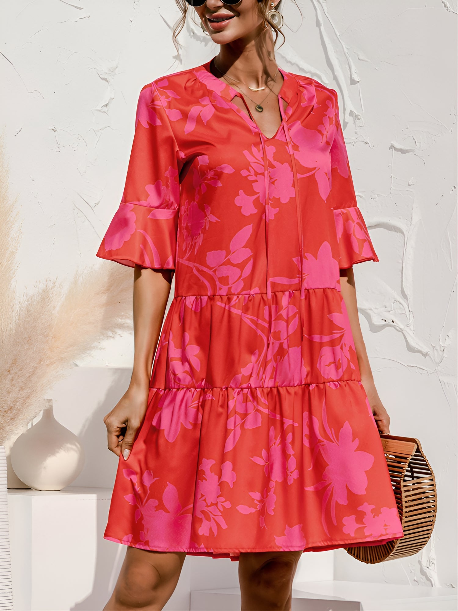 Rose Red - Model wearing a woven leopard print v-neck tiered mini dress with flutter sleeves and neckline tie details, holding a structured bamboo handbag.