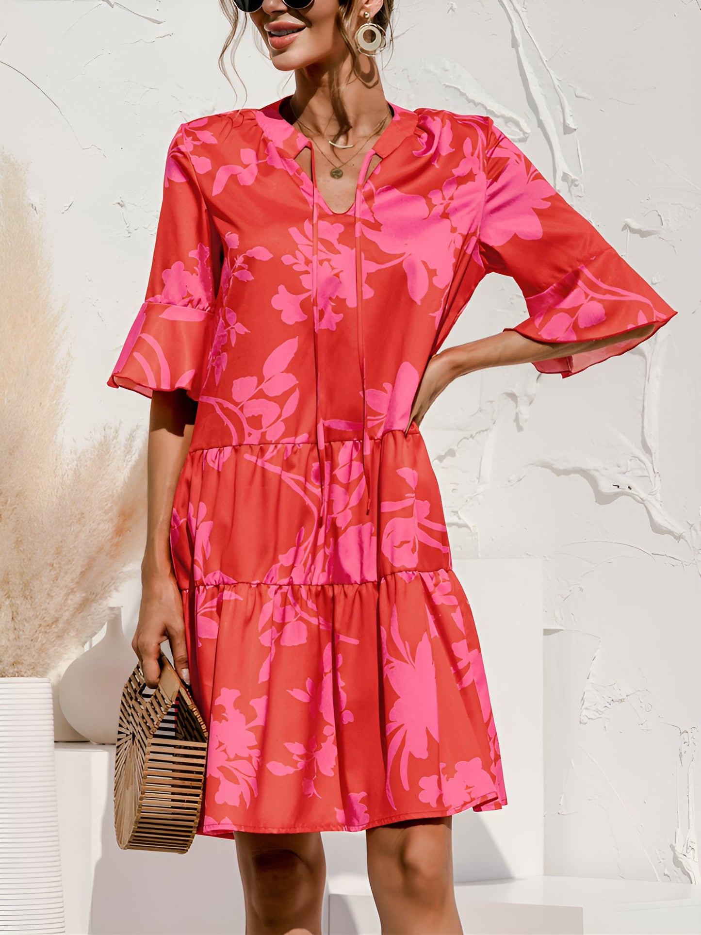 Rose Red - Model wearing a woven leopard print v-neck tiered mini dress with flutter sleeves and neckline tie details, holding a structured bamboo handbag.