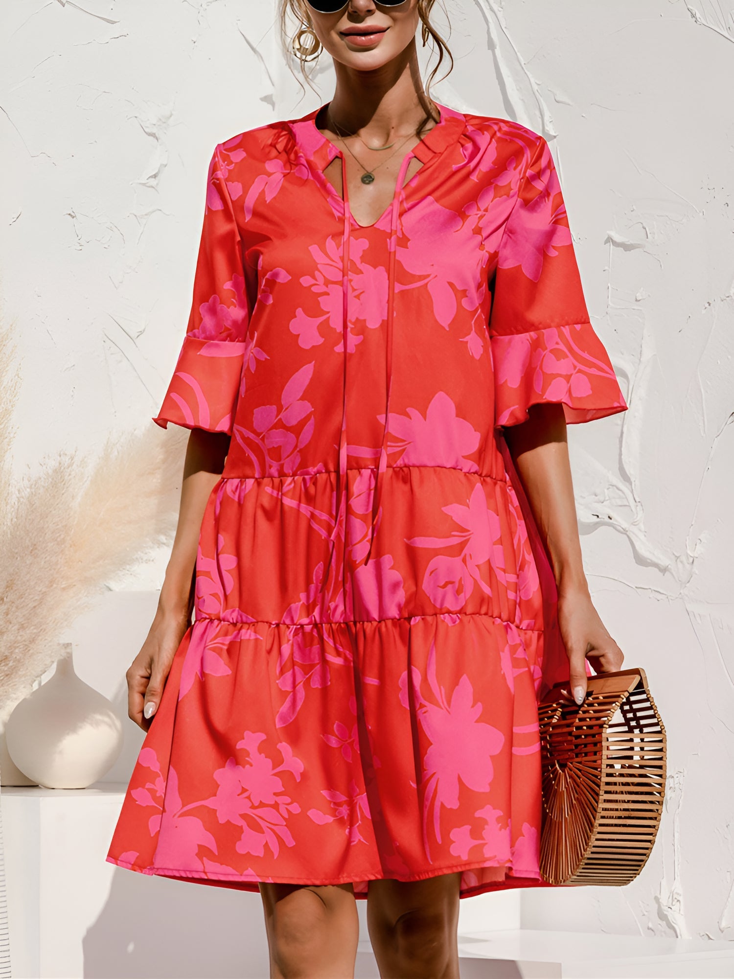 Rose Red - Model wearing a woven leopard print v-neck tiered mini dress with flutter sleeves and neckline tie details, holding a structured bamboo handbag.