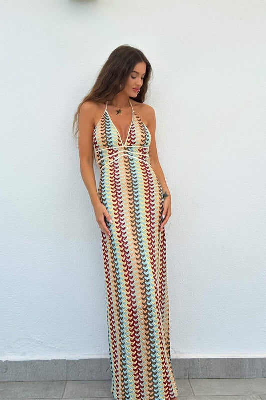 Multi - Woman wearing a long, halterneck maxi dress featuring a multi-coloured chevron knit pattern and a plunging V-neckline.