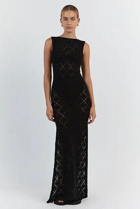 Black - A woman modelling a cream-coloured, sleeveless maxi dress featuring an intricate geometric open-knit pattern, a high neckline, and a high side slit.