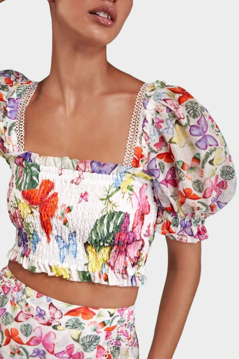 White - Women's white cropped blouse featuring a colourful butterfly and botanical print, a shirred bodice, square neckline, and short puff sleeves, paired with a matching tiered mini skirt.