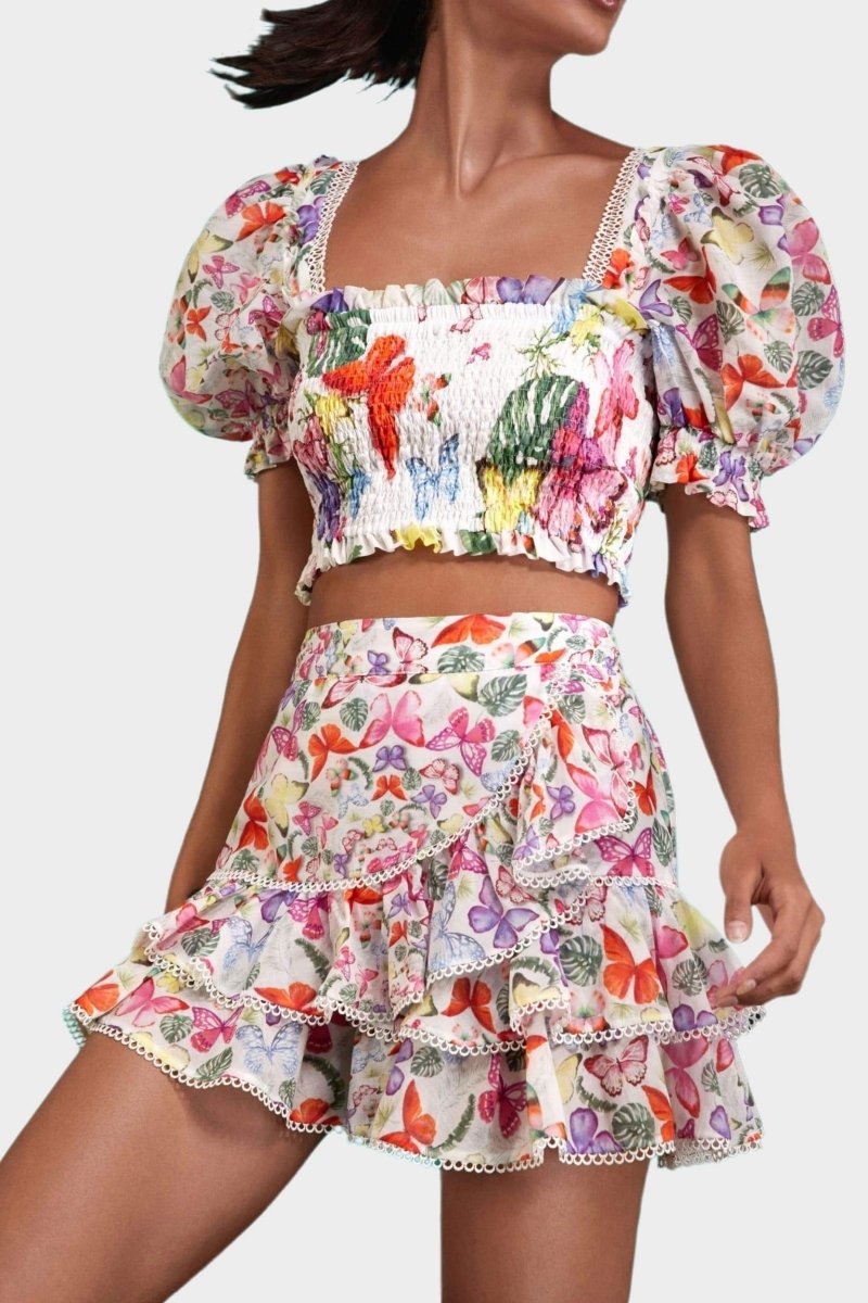 White - Women's white cropped blouse featuring a colourful butterfly and botanical print, a shirred bodice, square neckline, and short puff sleeves, paired with a matching tiered mini skirt.