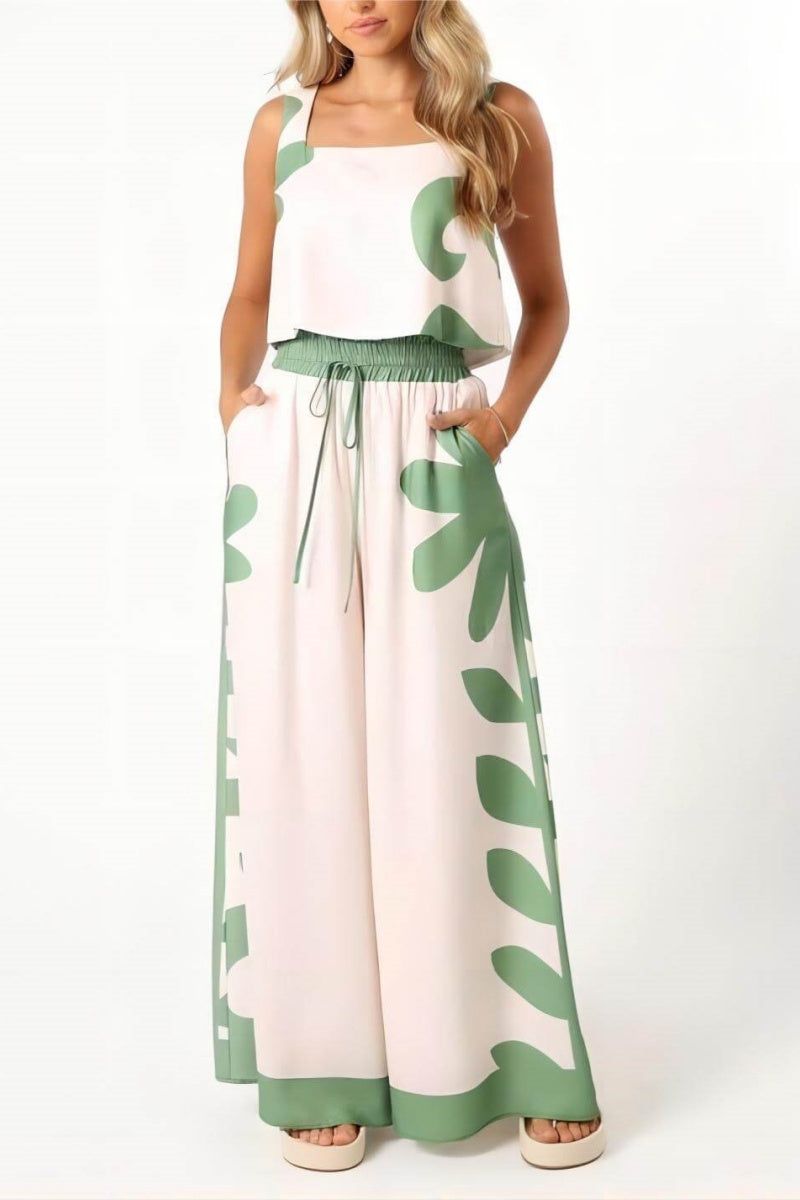 White - A woman wearing a white two-piece summer set featuring a cropped square-neck top and high-waisted wide-leg trousers, both adorned with a bold green abstract botanical print.