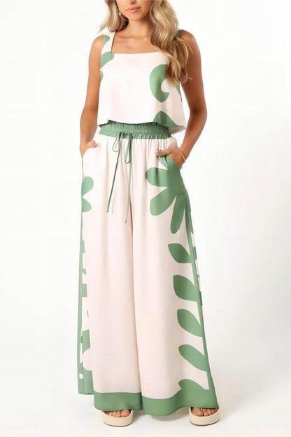 White - A woman wearing a white two-piece summer set featuring a cropped square-neck top and high-waisted wide-leg trousers, both adorned with a bold green abstract botanical print.
