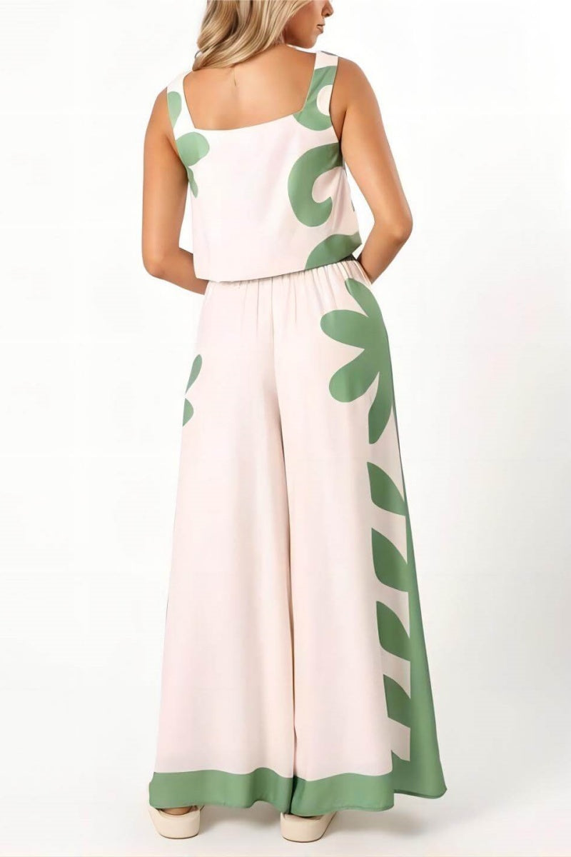 A woman wearing a white two-piece summer set featuring a cropped square-neck top and high-waisted wide-leg trousers, both adorned with a bold green abstract botanical print.