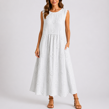 White - Sleeveless midaxi smock dress featuring tufted floral patterns, a round neckline, and side pockets, styled on a model against a plain background.