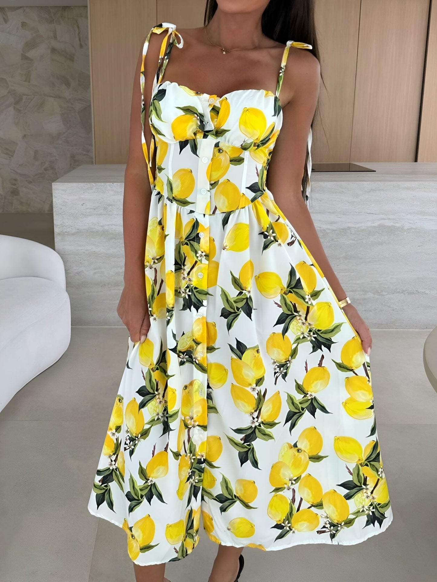 Yellow - Woman modelling a printed A-line midi dress featuring a sweetheart neckline, button-down bodice, and adjustable tie-straps.