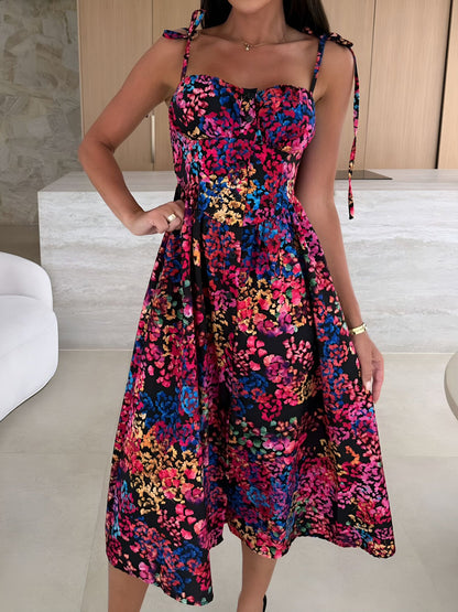 Black - Woman modelling a printed A-line midi dress featuring a sweetheart neckline, button-down bodice, and adjustable tie-straps.