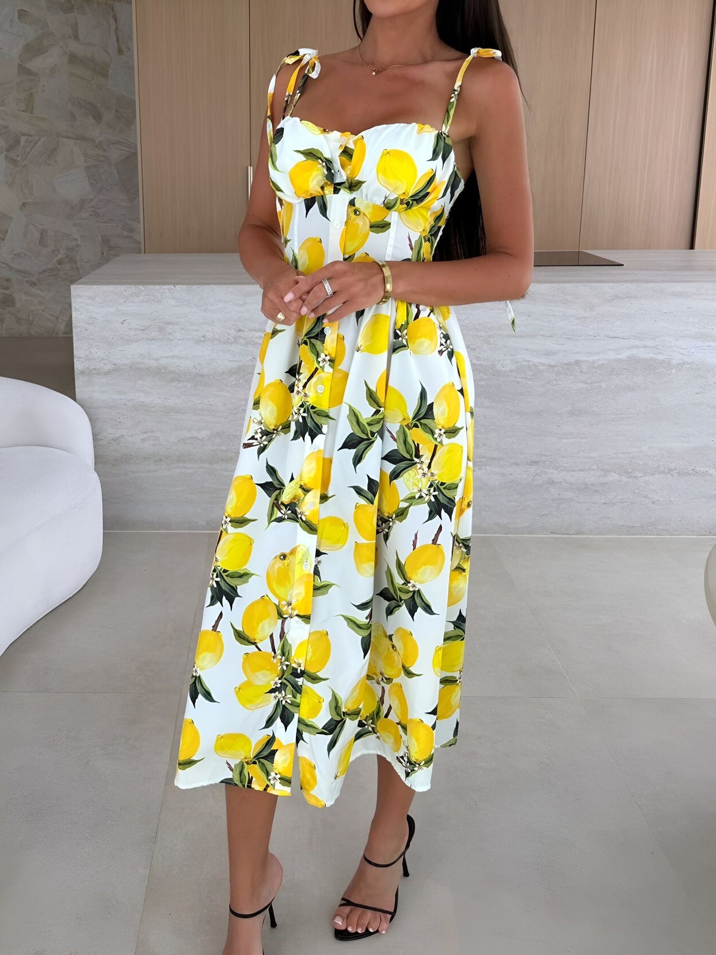 Yellow - Woman modelling a printed A-line midi dress featuring a sweetheart neckline, button-down bodice, and adjustable tie-straps.