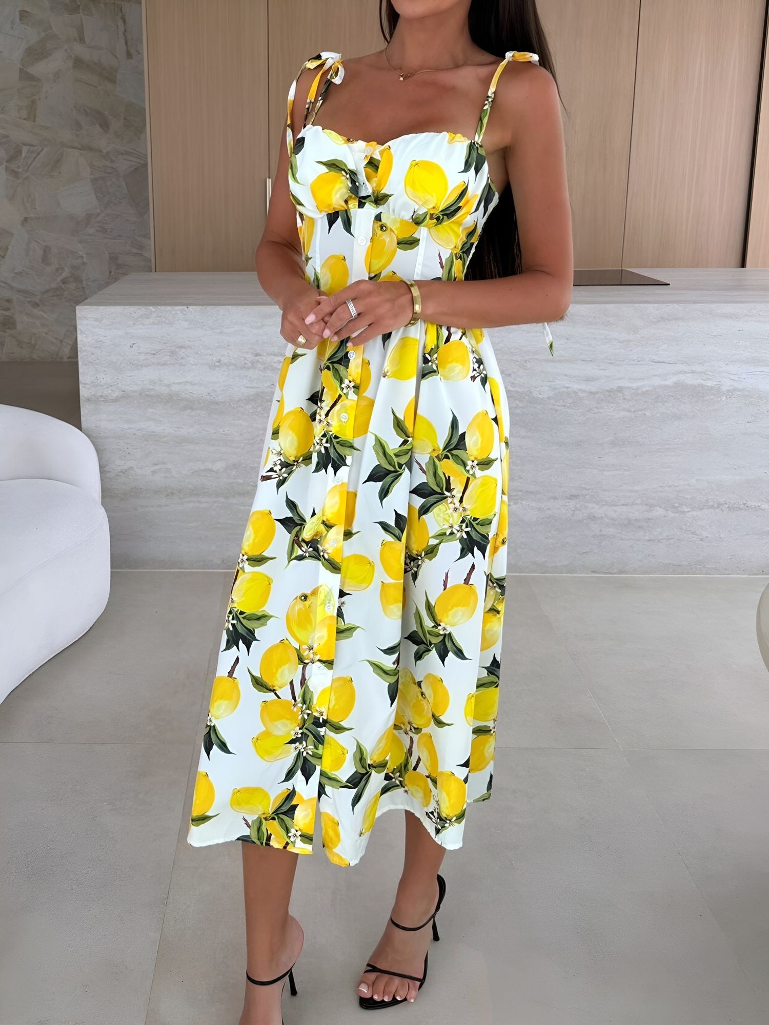 Yellow - Woman modelling a printed A-line midi dress featuring a sweetheart neckline, button-down bodice, and adjustable tie-straps.