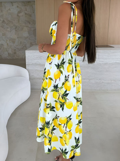 Yellow - Woman modelling a printed A-line midi dress featuring a sweetheart neckline, button-down bodice, and adjustable tie-straps.