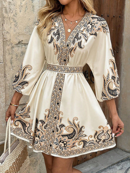 Apricot - Woman wearing a woven boho V-neck mini shirt dress with ornate paisley print and voluminous sleeves, holding a woven straw bag outdoors.