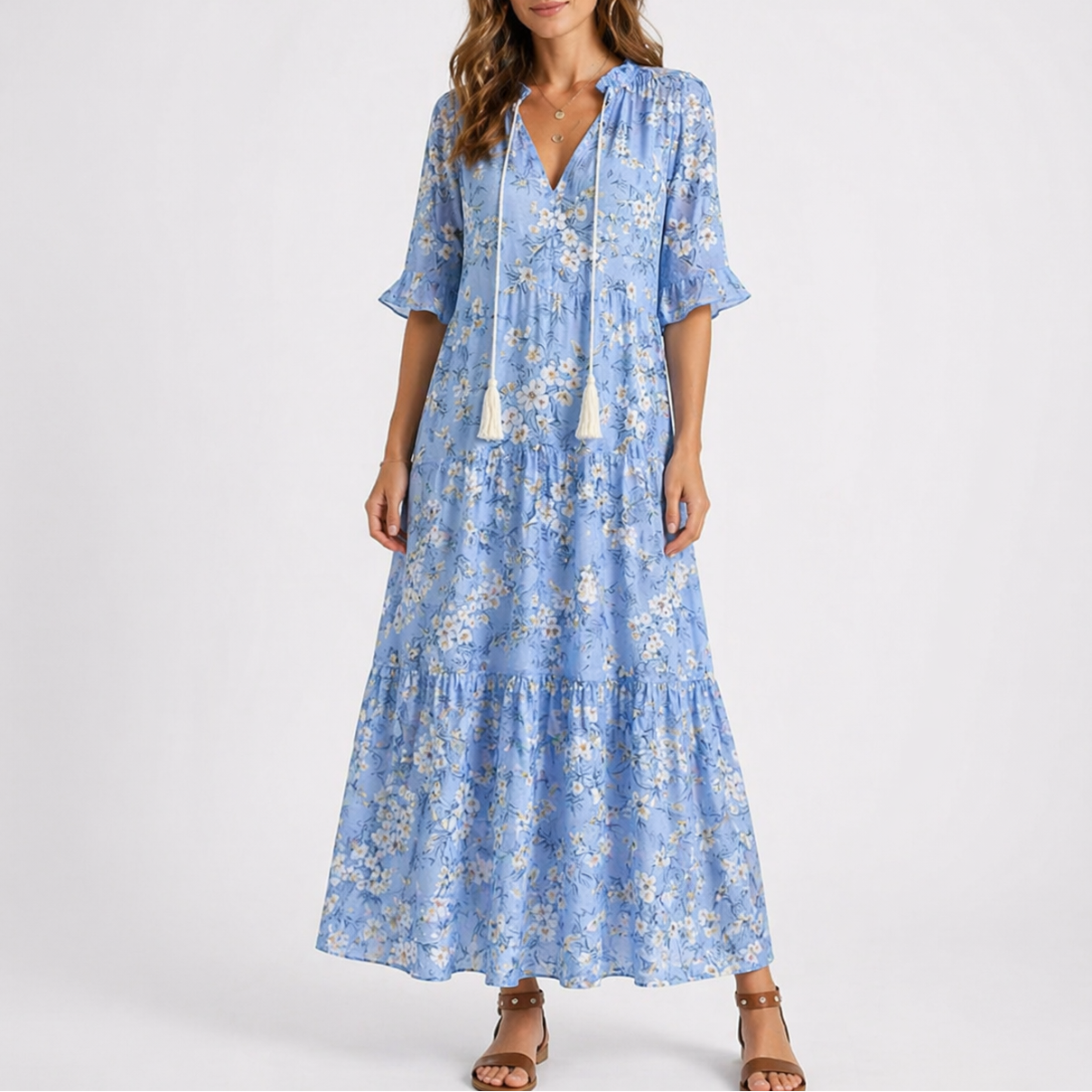 Blue & White - Model wearing a woven geometric ikat pattern maxi dress featuring a V-neckline with tassel ties, 3/4 sleeves, and a tiered hemline.
