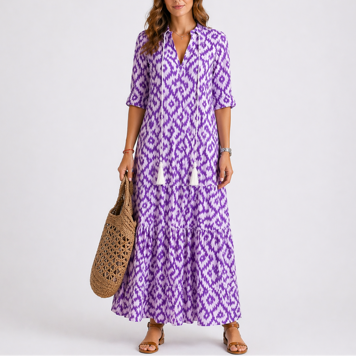 Purple - Model wearing a woven geometric ikat pattern maxi dress featuring a V-neckline with tassel ties, 3/4 sleeves, and a tiered hemline.