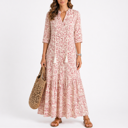 Red - Model wearing a woven geometric ikat pattern maxi dress featuring a V-neckline with tassel ties, 3/4 sleeves, and a tiered hemline.