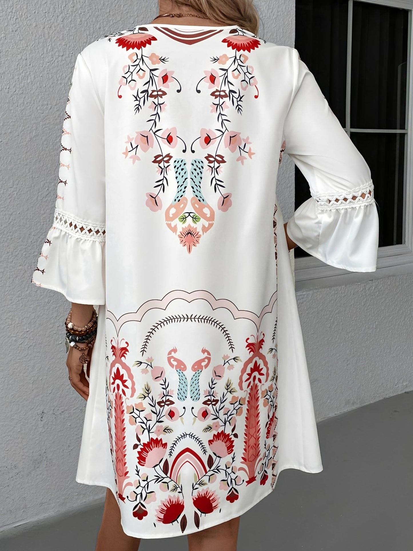 Red - Woman wearing a bohemian floral print V-neck tunic dress with crochet trim and three-quarter sleeves, styled with a straw hat and woven tote bag.