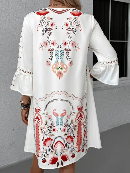 Red - Woman wearing a bohemian floral print V-neck tunic dress with crochet trim and three-quarter sleeves, styled with a straw hat and woven tote bag.