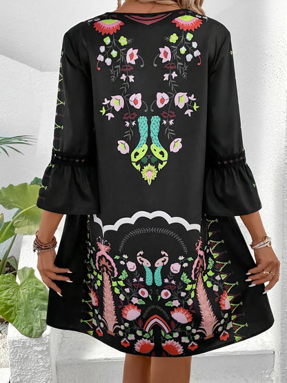 Black - Woman wearing a bohemian floral print V-neck tunic dress with crochet trim and three-quarter sleeves, styled with a straw hat and woven tote bag.