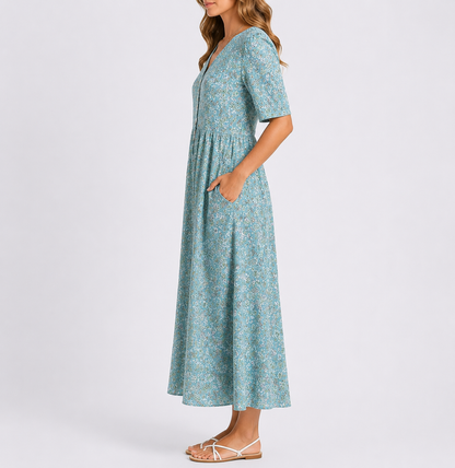 Woman wearing a floral print short-sleeve smock midi dress with a gathered waist and side pockets.