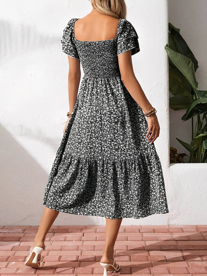 Black - Woman wearing a woven floral square-neck midi dress with a smocked bodice, flutter sleeves, and a tiered skirt, styled with a straw hat and woven bag.