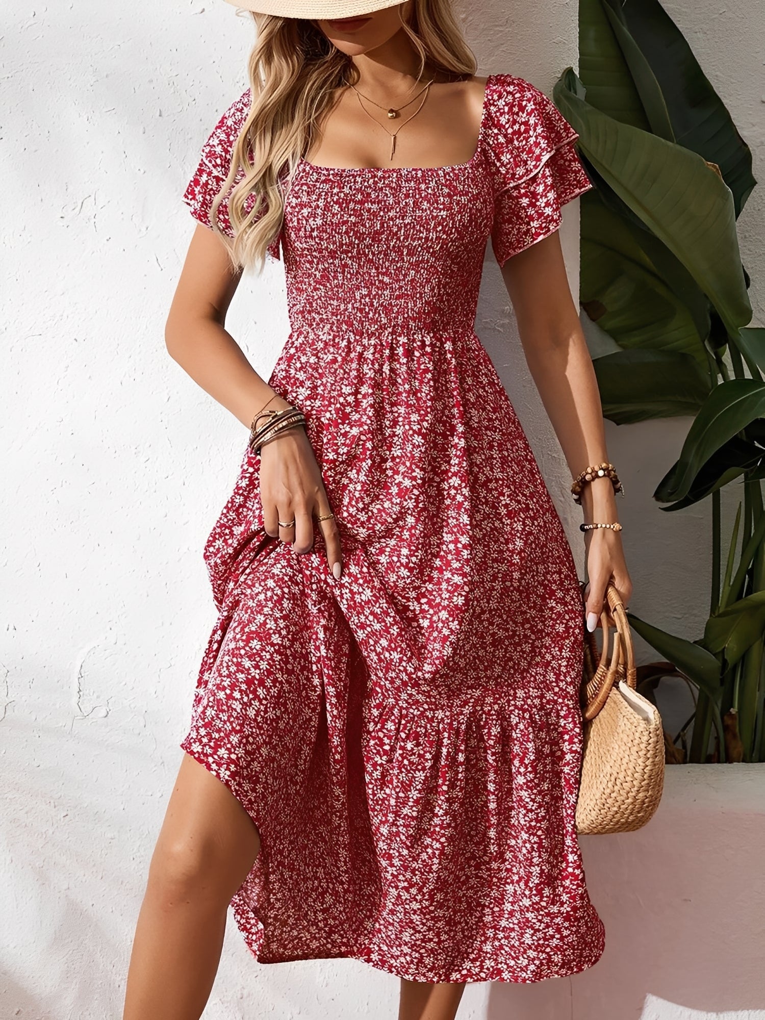 Red - Woman wearing a woven floral square-neck midi dress with a smocked bodice, flutter sleeves, and a tiered skirt, styled with a straw hat and woven bag.