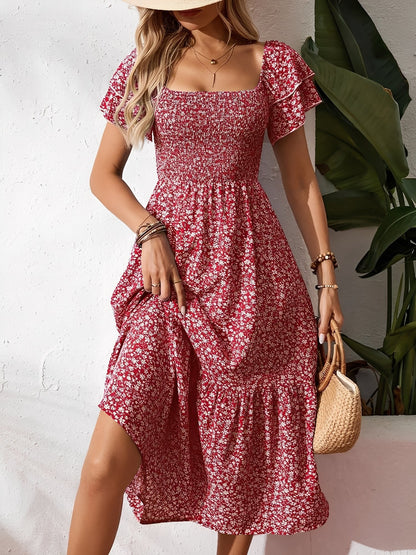 Red - Woman wearing a woven floral square-neck midi dress with a smocked bodice, flutter sleeves, and a tiered skirt, styled with a straw hat and woven bag.