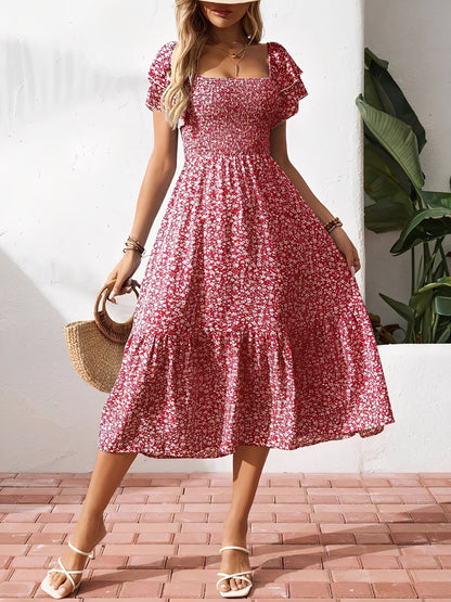 Red - Woman wearing a woven floral square-neck midi dress with a smocked bodice, flutter sleeves, and a tiered skirt, styled with a straw hat and woven bag.