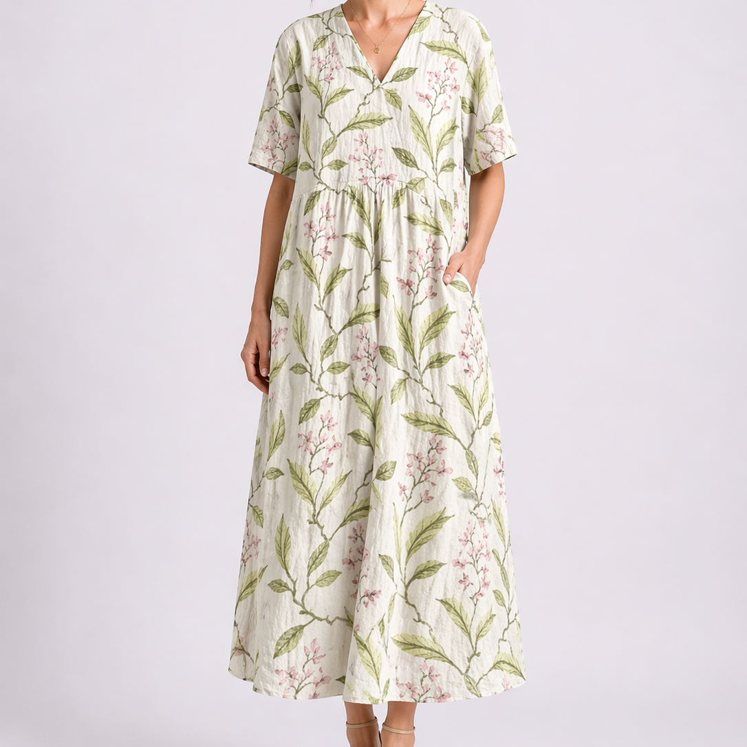 Floral White - Woman wearing a woven floral V-neck maxi dress with short sleeves and side pockets.