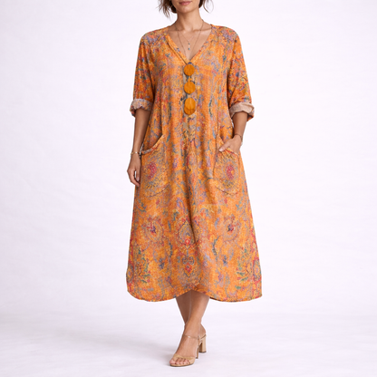 Orange - Model wearing a woven paisley print relaxed midaxi dress with a v-neckline, rolled sleeves, large front buttons, and patch pockets.